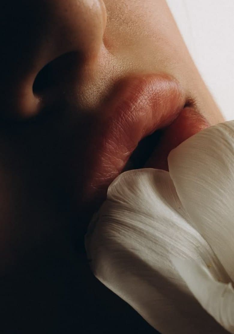 A close-up of lips beside a white flower petal